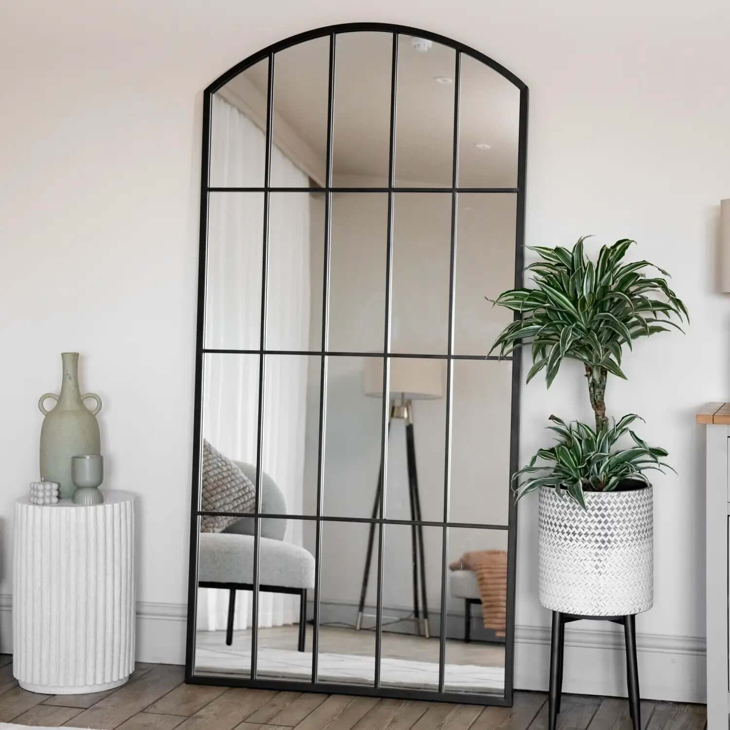 Arched window-pane style mirror with black metal frame divided into sections.