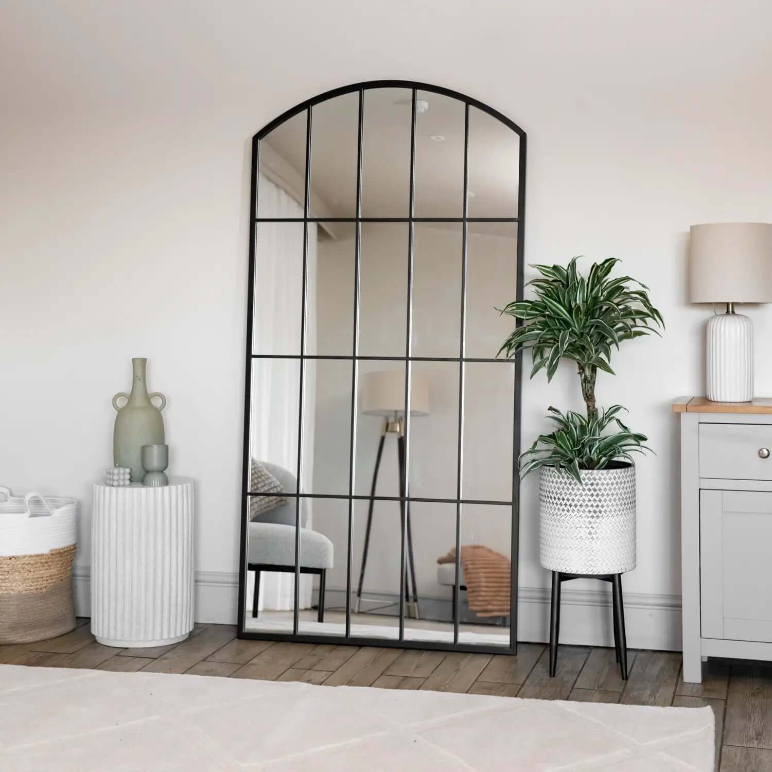 Arched black metal-framed mirror with grid pattern.