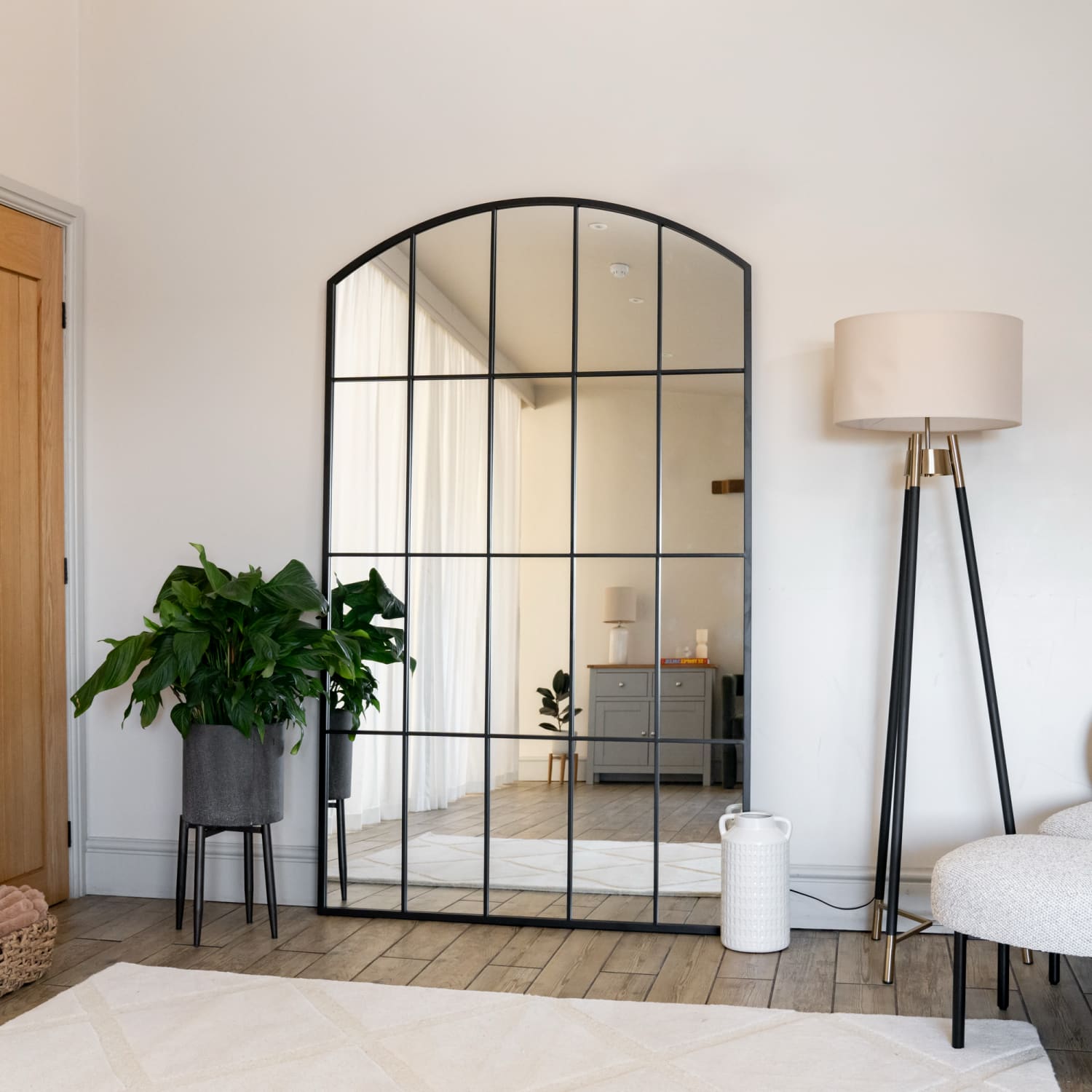 Arched window-style mirror with black metal grid pattern.