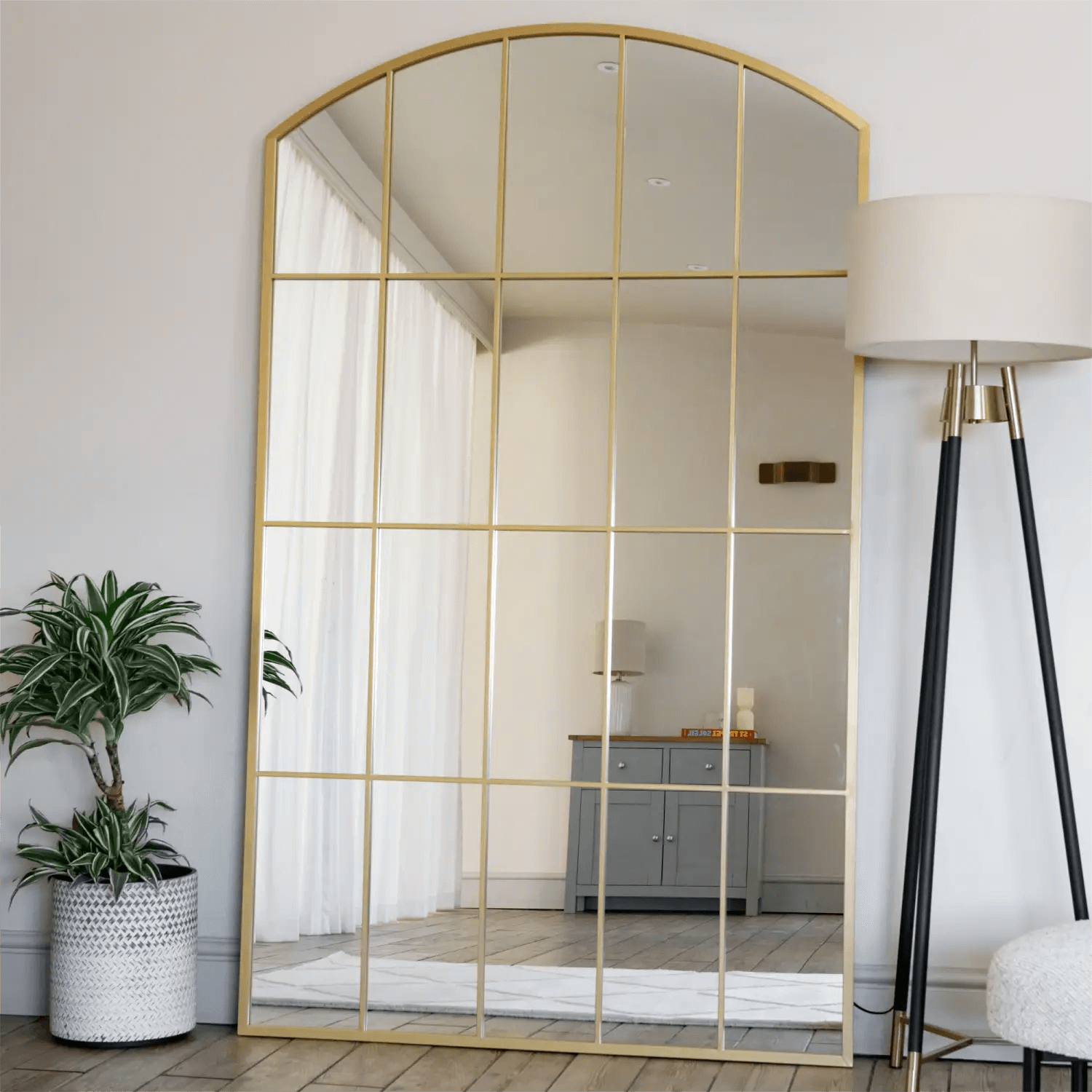 Arched gold-framed mirror with windowpane grid pattern.