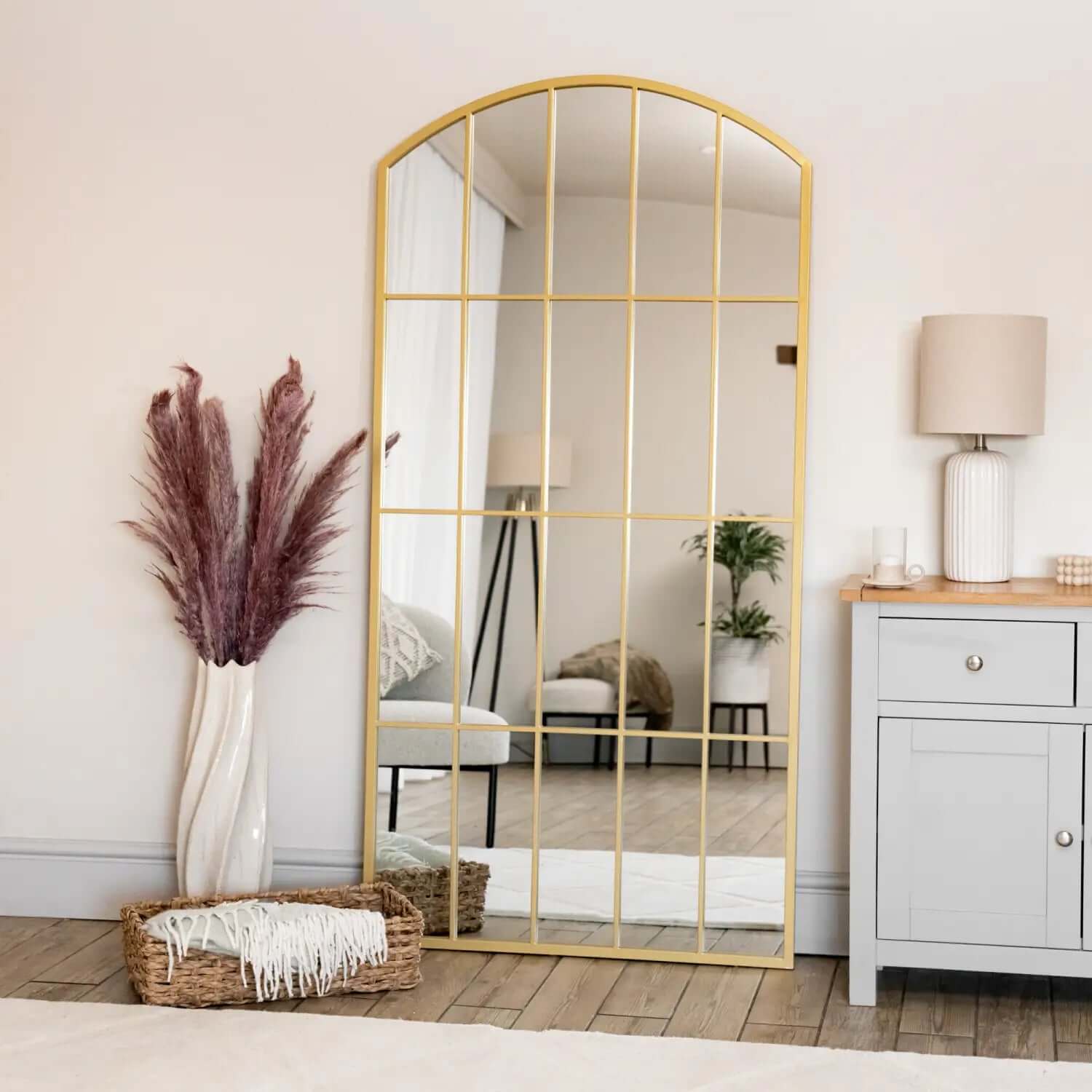 Arched gold-framed mirror with vertical grid pattern.