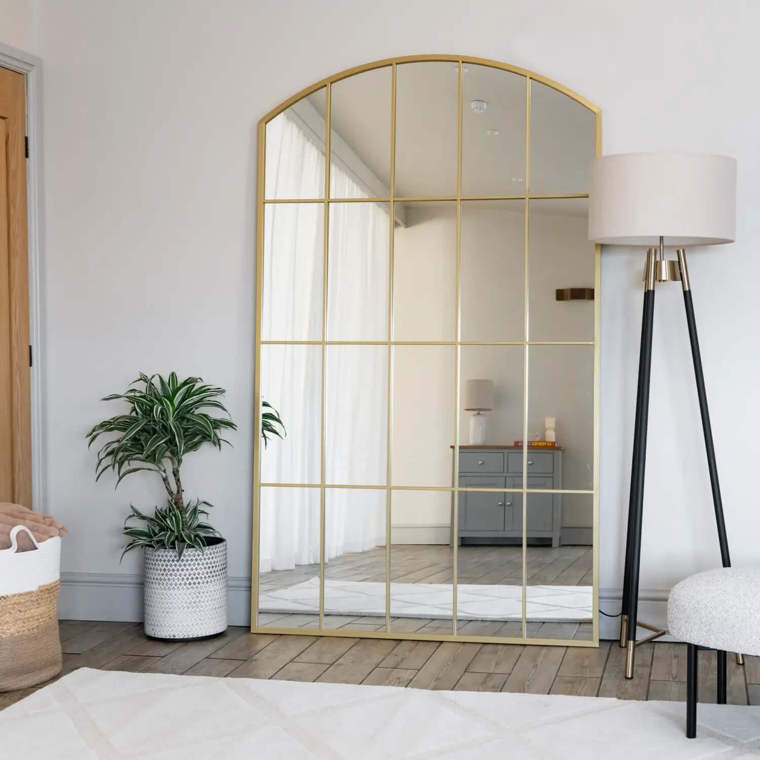 Arched gold-framed mirror with windowpane grid pattern.