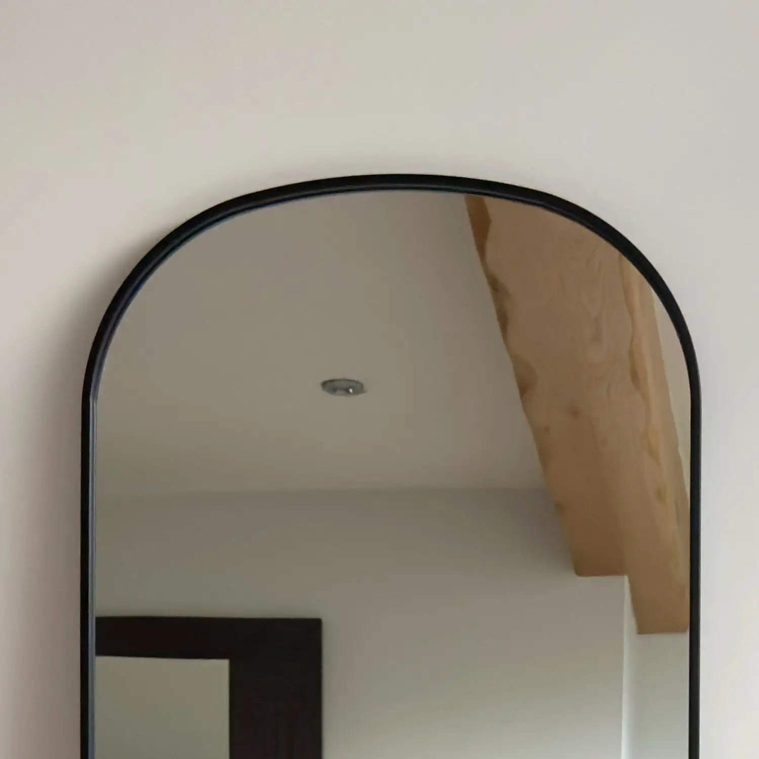 Arched mirror with a thin black metal frame.