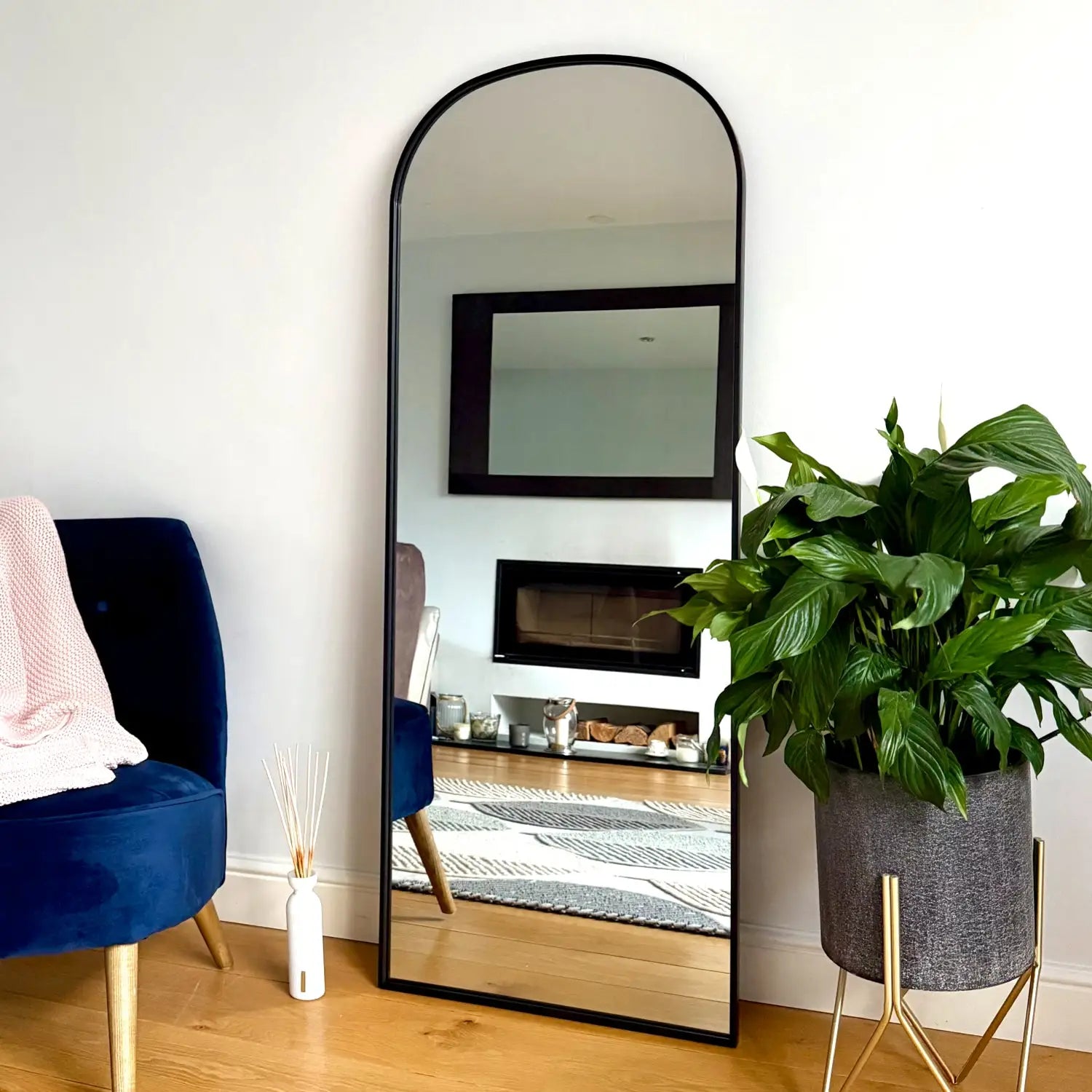 Arched black-framed floor mirror.