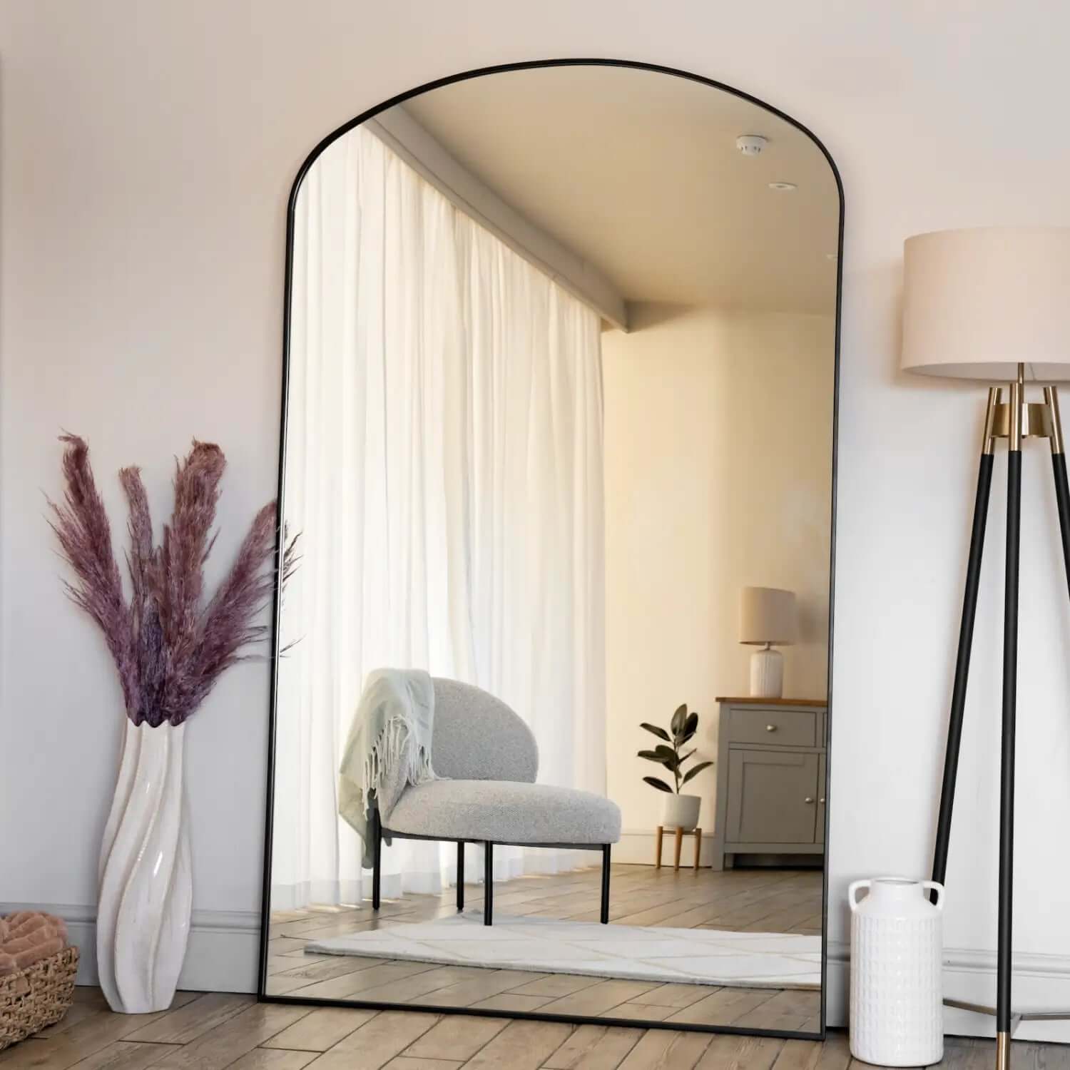 Arched floor mirror with a thin black metal frame.