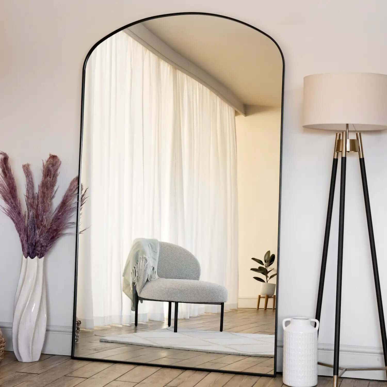 Arched floor mirror with a thin black metal frame.