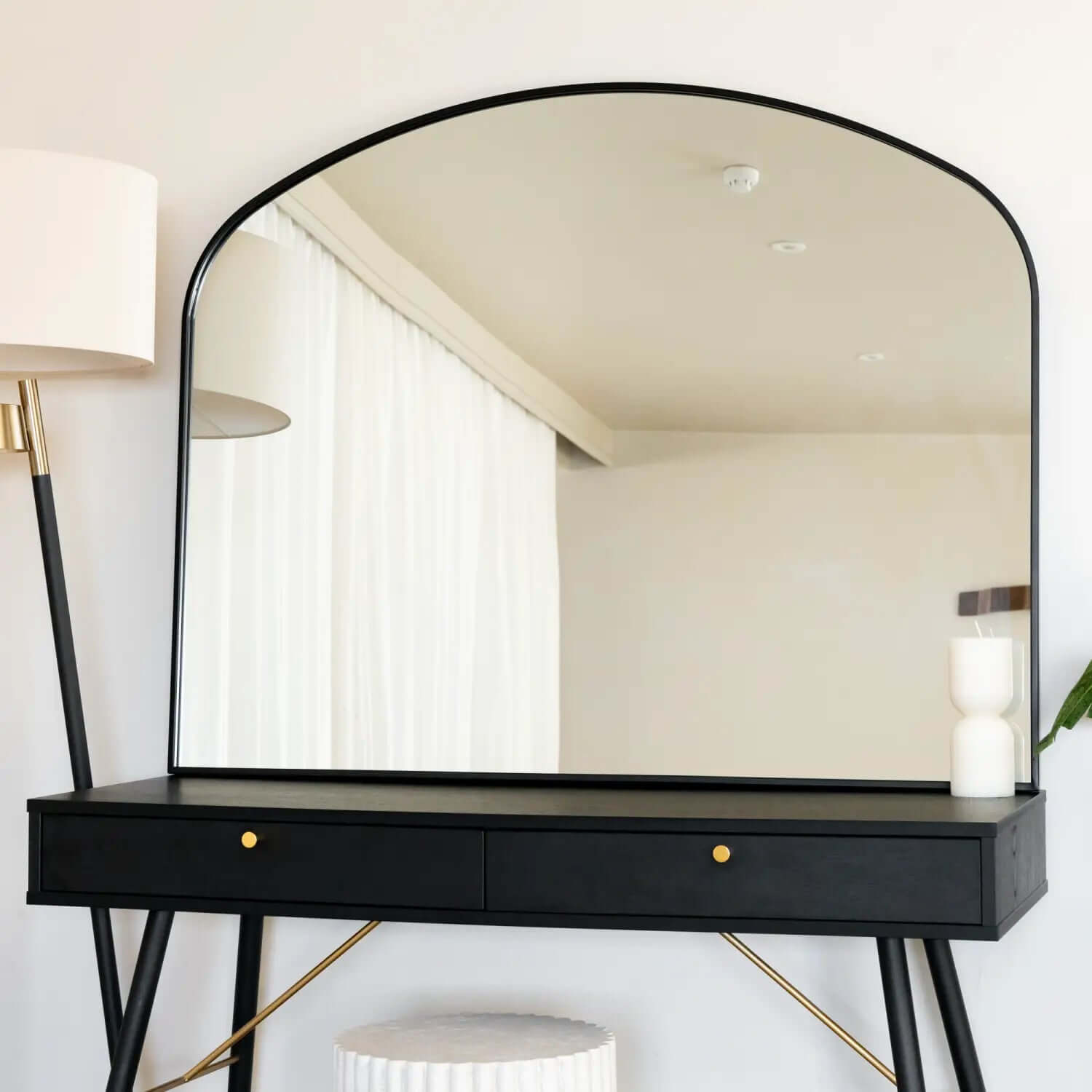 Black vanity table with an arched mirror and brass accents.