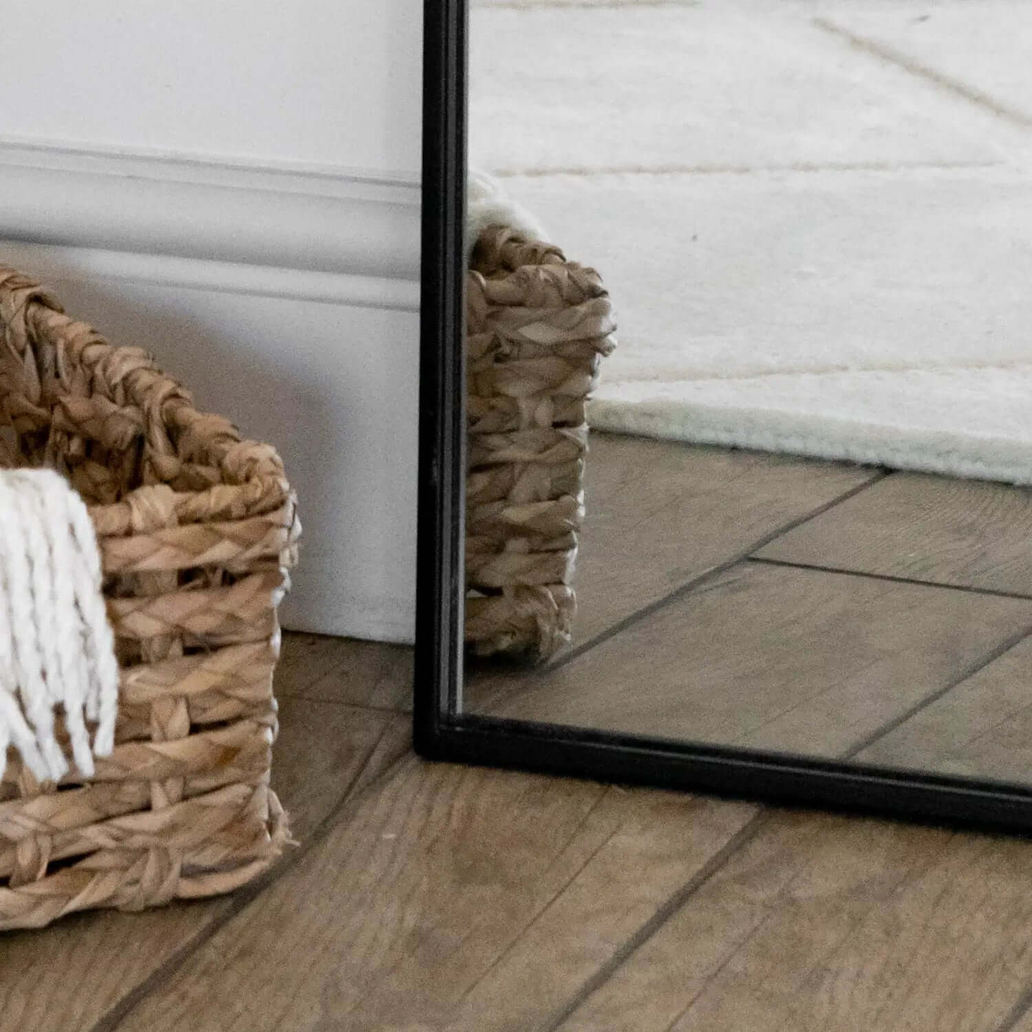 Woven basket containing white towels or linens next to a mirror.