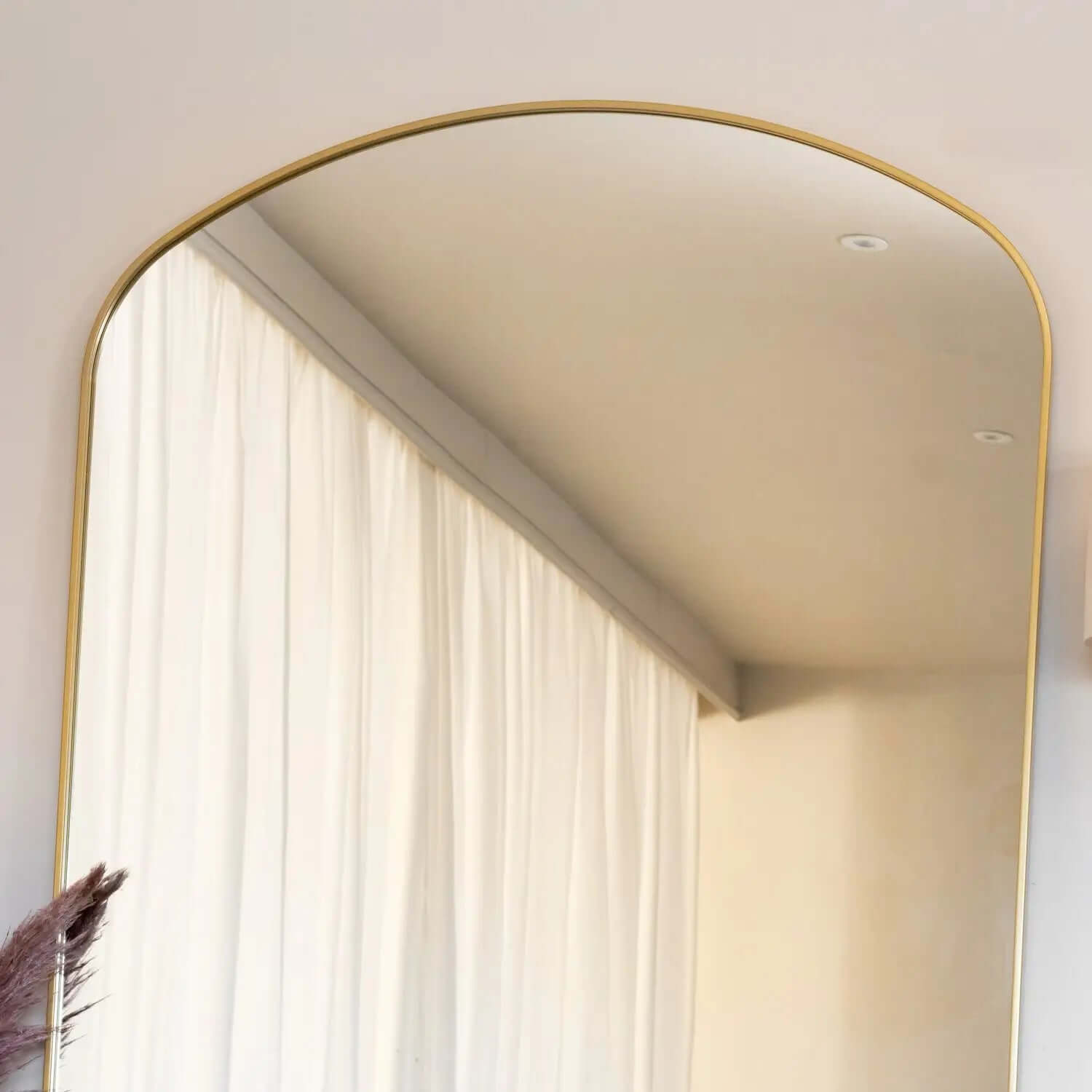 Arched mirror with a thin gold frame.