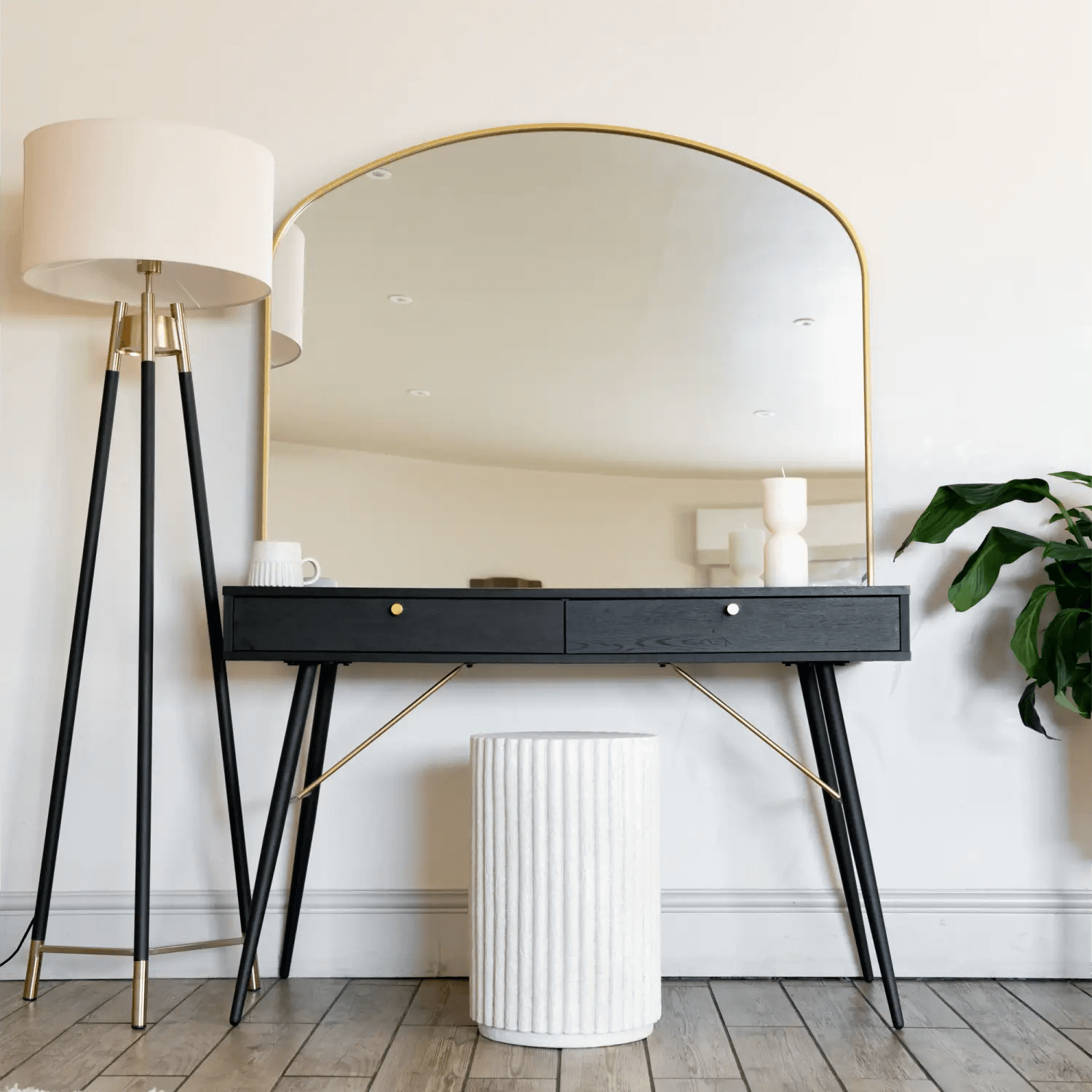 Modern black console table with drawers and an arched gold-rimmed mirror.